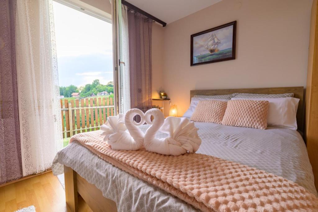 two swans are sitting on a bed with a window at Kuca za odmor Vinica breg in Varaždin