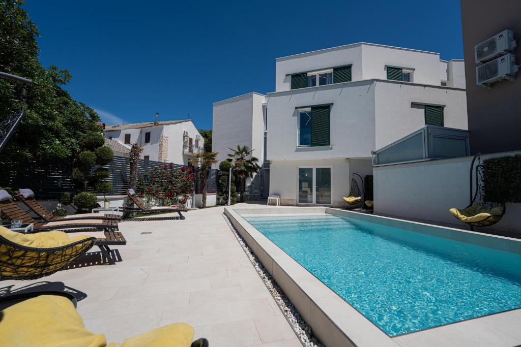 a house with a swimming pool next to a building at Avis Hotel in Novalja