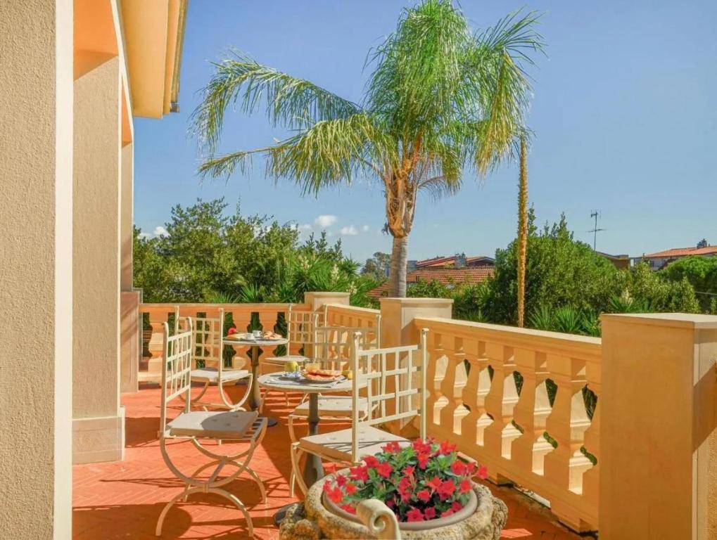 a patio with chairs and tables and a palm tree at LaTorrettaLoano Affittacamere in Loano