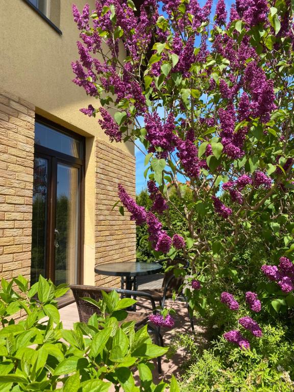 a picnic table in front of a building with purple flowers at ATOSTOGAUTI GERA in Palanga