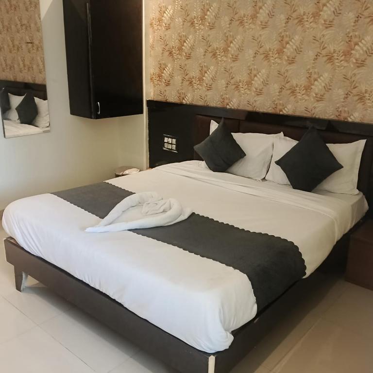 a bedroom with a bed with white sheets and pillows at Udupi Grand Lodging and Boarding in Chākan