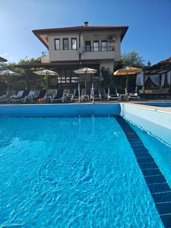 a large blue swimming pool with a house in the background at Бадевски рай-къща Надежда in Badewzi