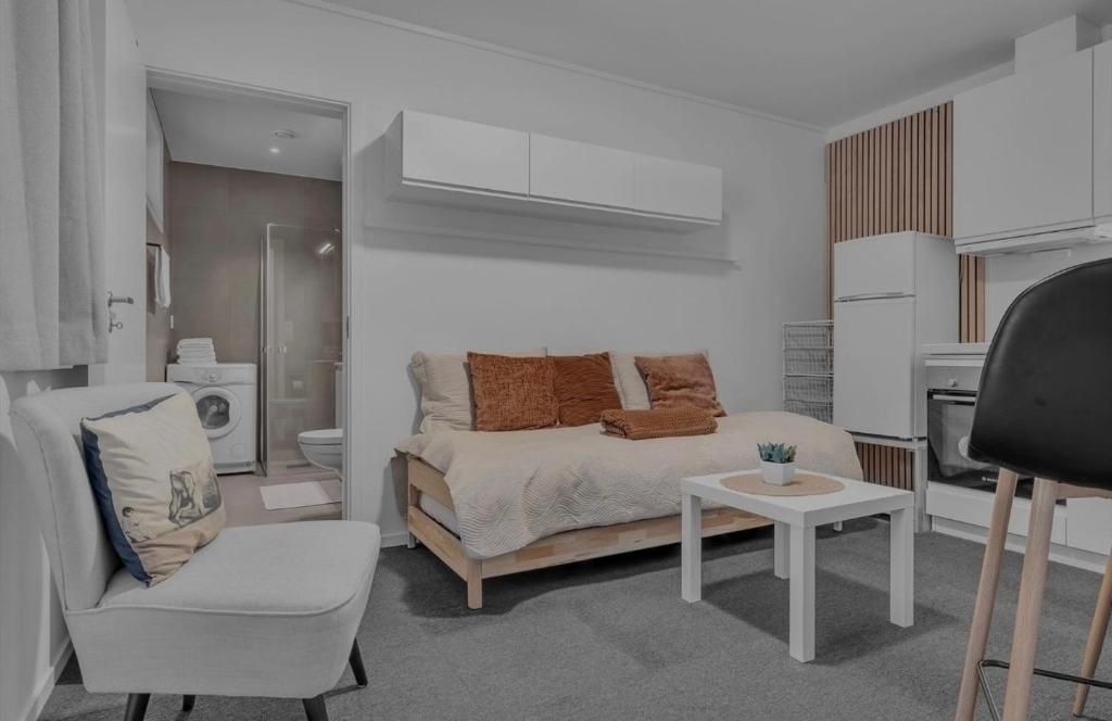 a bedroom with a bed and a chair and a table at Nordheim studio apartment in Tromsø