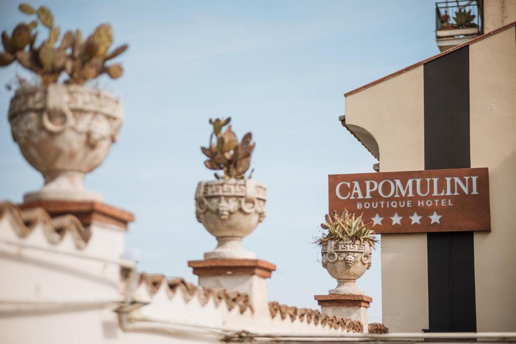a sign on the side of a building with potted plants at Capomulini Boutique Hotel in Capo Mulini