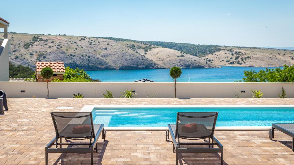 two chairs sitting in front of a swimming pool at Villa Amarea in Lopar