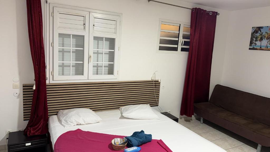a bedroom with a bed and a window and a couch at Le Pavillon Ananas in Gros-Morne