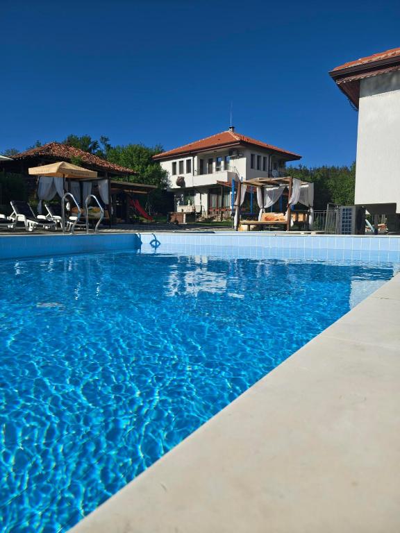 a swimming pool with blue water in front of a house at Бадевски рай-къща Любов in Badewzi