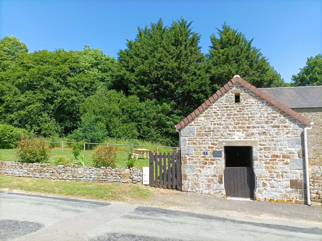 a stone building with a gate and a fence at La Cahute, gîte étape in La Forêt-Auvray