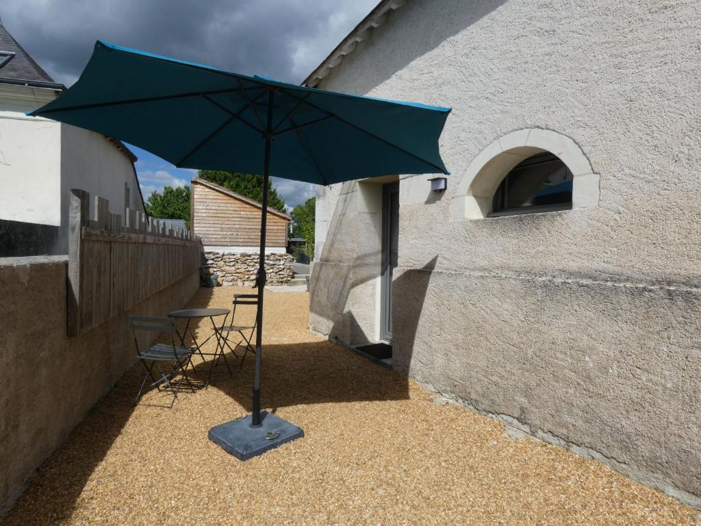 a green umbrella sitting next to a building at Au long du cher in Véretz