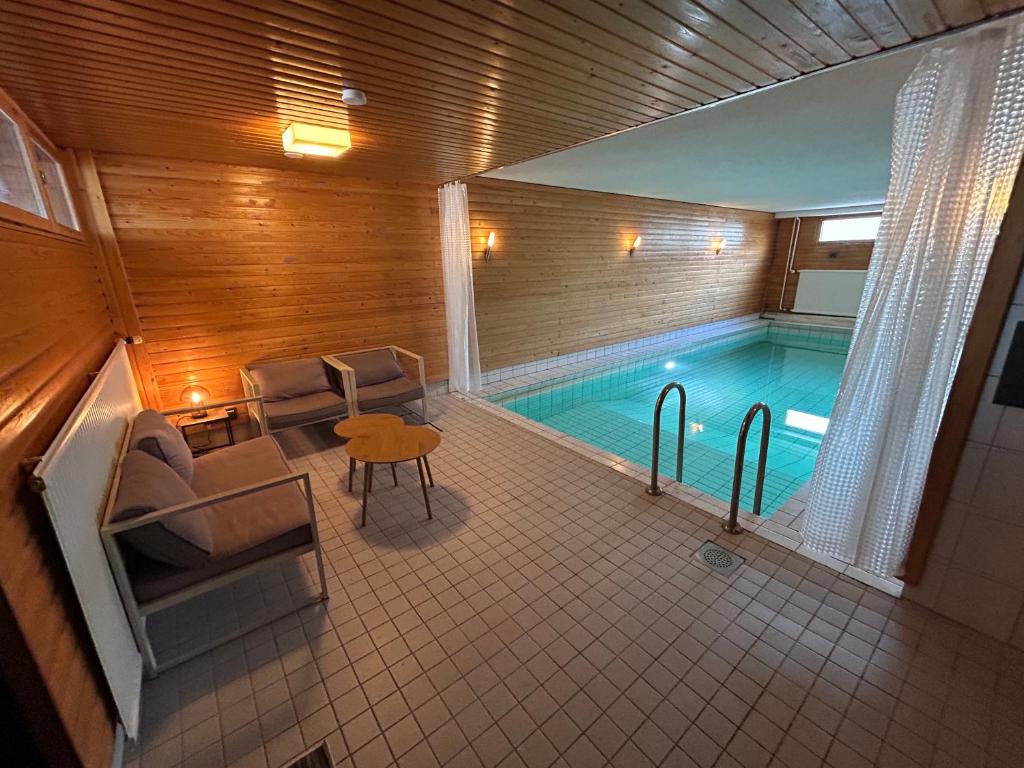 a swimming pool with chairs and a table in front of it at Large apartment in the centre of Jyväskylä with private swimming pool and sauna in Jyväskylä