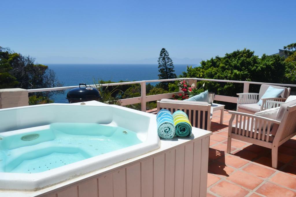 a hot tub on a patio with the ocean in the background at Seabreeze Luxury Two Bedroom Self Catering Penthouse in Simonʼs Town