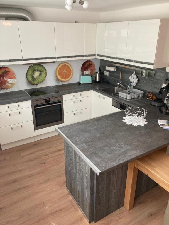 a kitchen with white cabinets and a gray counter top at Peter's Ferienwohnung Nahe Rust, Kehl, Straßburg, Offenburg in Neuried