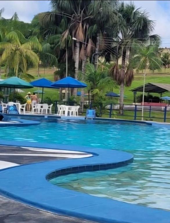 a pool with palm trees and blue umbrellas at ECO CHALÉ PARK CACHOEIRAS in Presidente Figueiredo