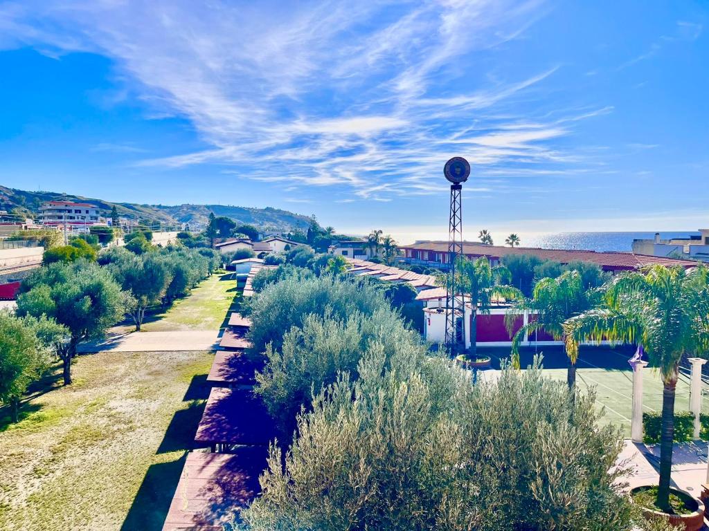 a street with trees and the ocean in the background at Villaggio Magna Grecia in Lazzaro
