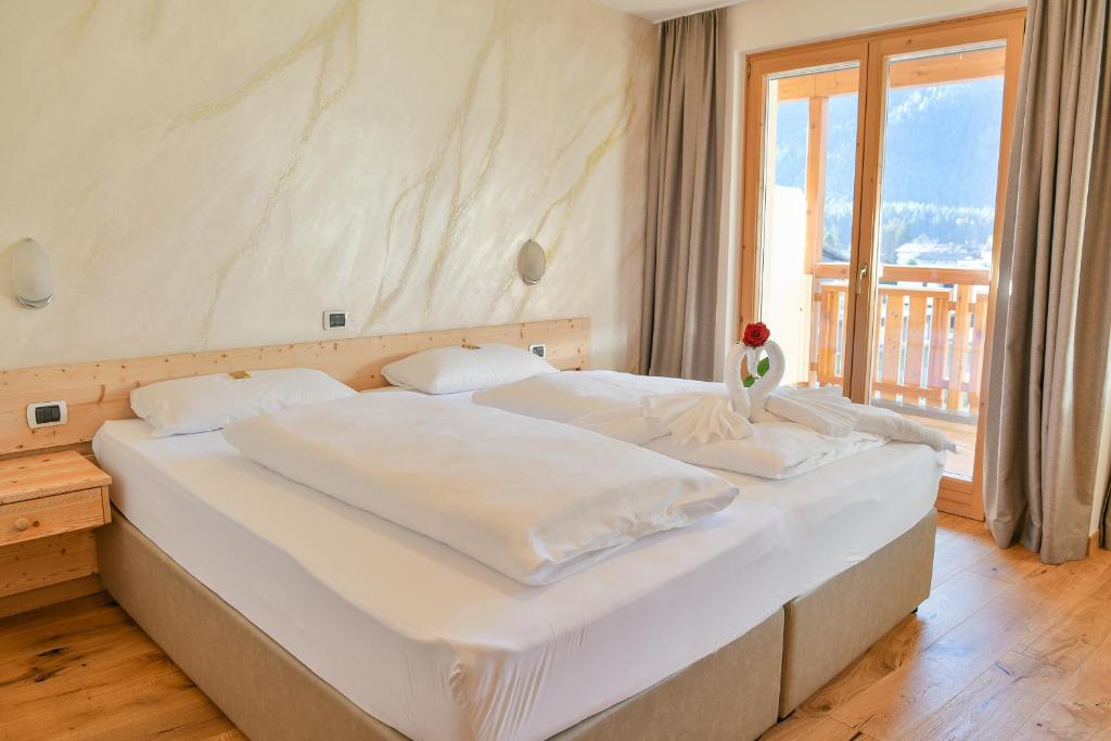 a bedroom with a large white bed with a window at Hotel Savoia in Dobbiaco