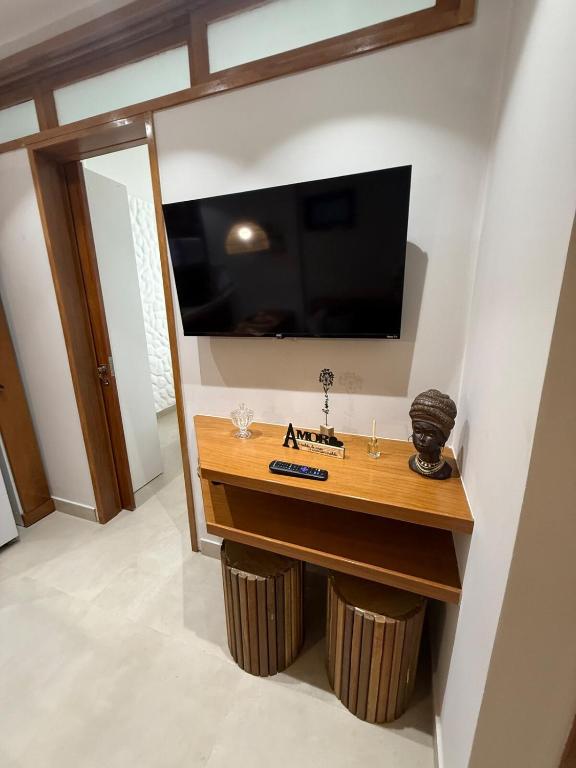 a room with a table with a television on a wall at Apartamento Guarapari temporada in Guarapari