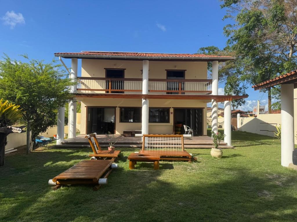 a house with two benches in front of it at Casa Com 2 Quartos Barra Serinhaem - BA in Ituberá