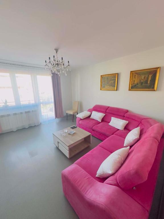 a living room with a pink couch and a table at Apartamenty na Pięknej 24-2 in Nowy Sącz