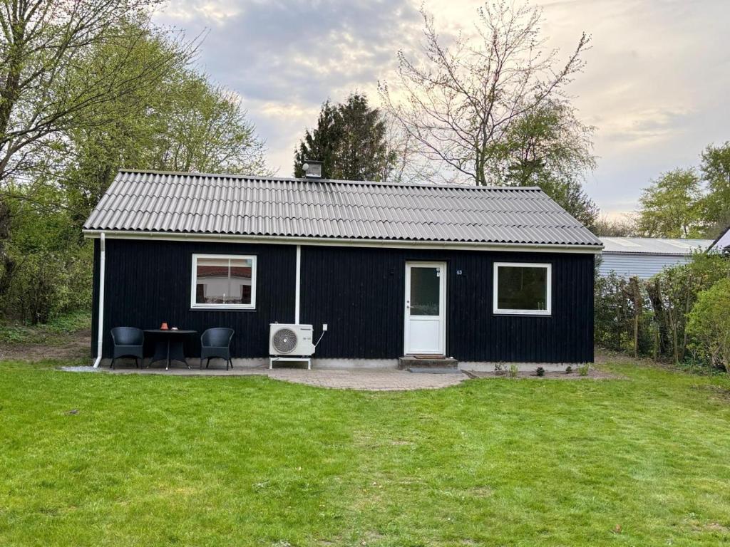 a black shed with a table and chairs in a yard at Dream house in Glesborg