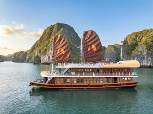 a cruise ship in the water with mountains in the background at Petit Prince Cruise in Cat Ba