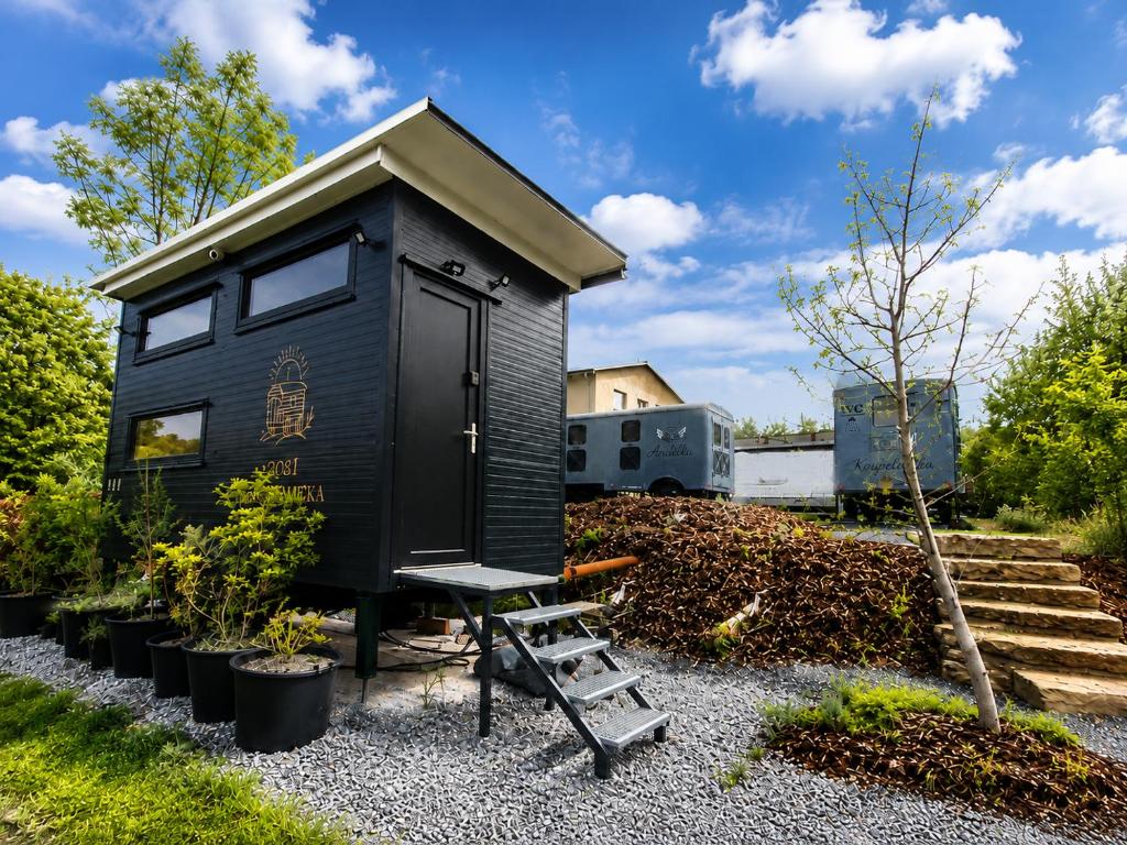 a black tiny house with a bench in a yard at Boží maringotka in Humpolec