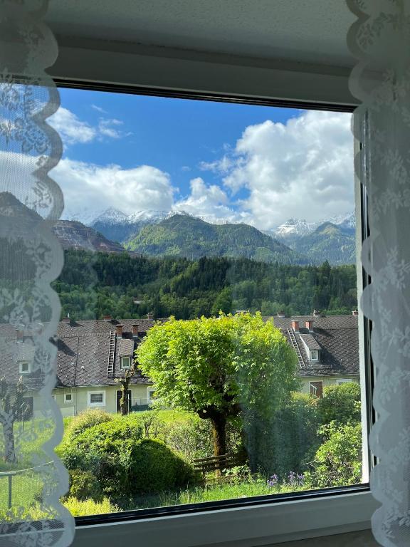 a window with a view of a tree and mountains at Panoramic Alpine Residence in Eisenerz