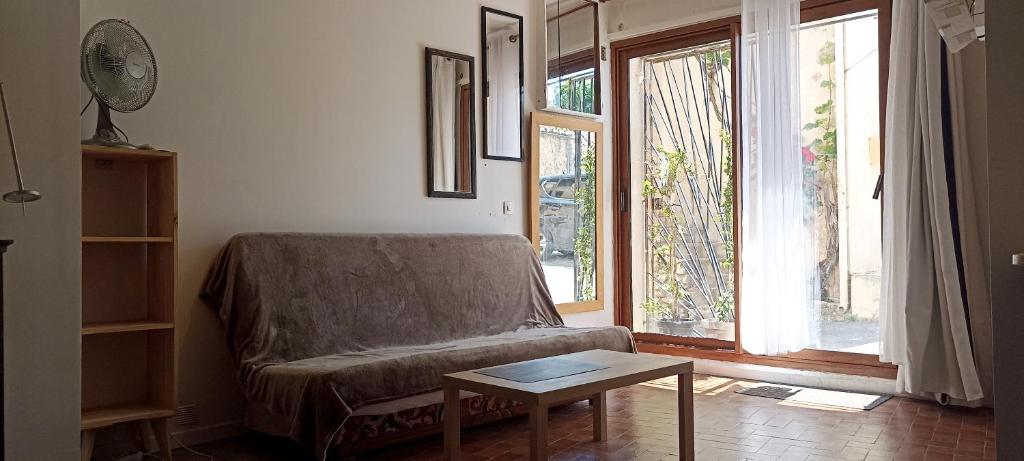 a living room with a couch and a table at Studio privé - maison de village in Valensole