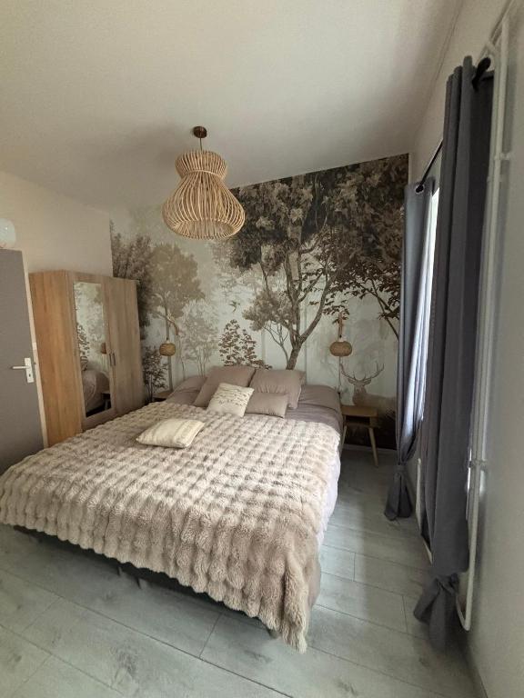 a bedroom with a bed and a wall with trees at Le studio «des Terroux » in Mortroux