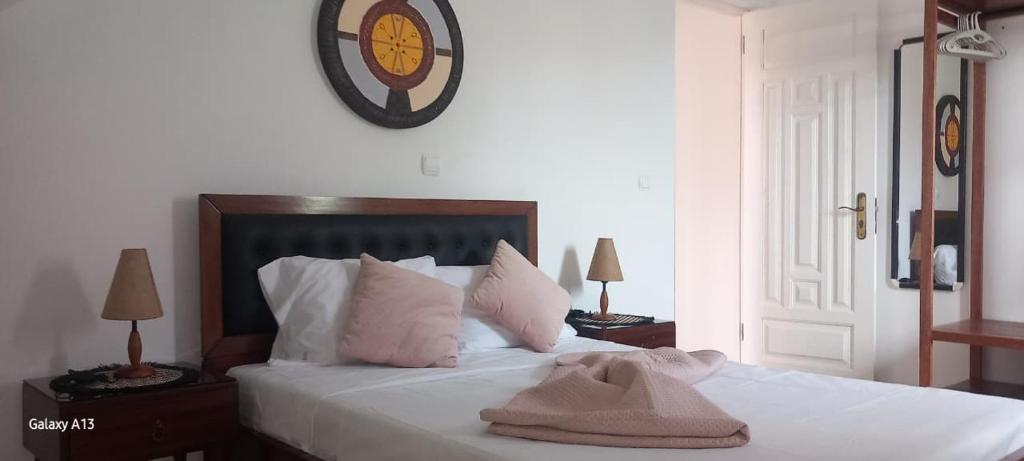 a bedroom with a bed with white sheets and pink pillows at Sunrise house in Ribeira Grande