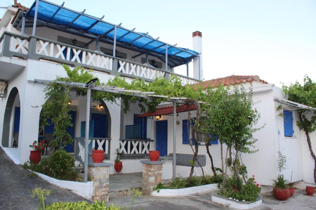 un edificio bianco con finestre blu e piante di Alexandra Sofia a Stafylos