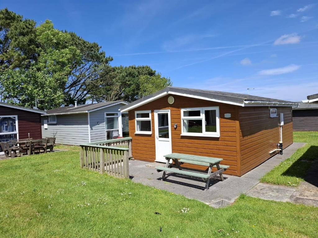 a small cabin with a picnic bench in a yard at Cosy Corner Cabin in Saint Merryn