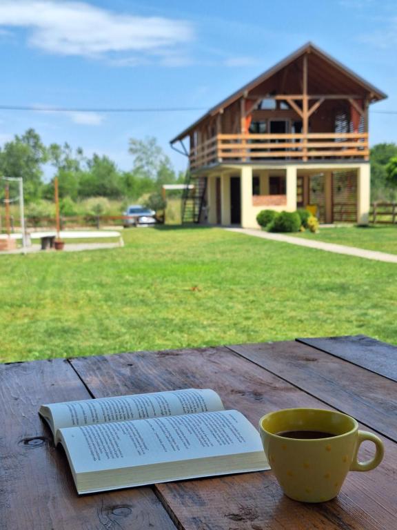 a book and a cup of coffee on a wooden table at Brvnara Bata - Vikendica na Drini in Lipnički Šor