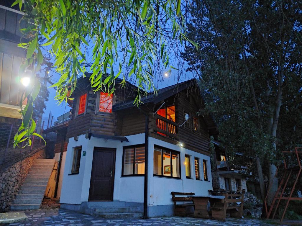 a wooden house with a lit up porch at night at Vikendica Jablaničko jezero in Jablanica