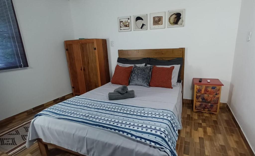 a bedroom with a large bed with orange and blue pillows at Casa Águas do Céu de Lumiar in Nova Friburgo