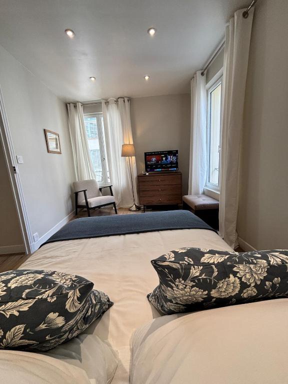 a bedroom with two beds with pillows and a television at La suite de Elise in Beaulieu-sur-Mer