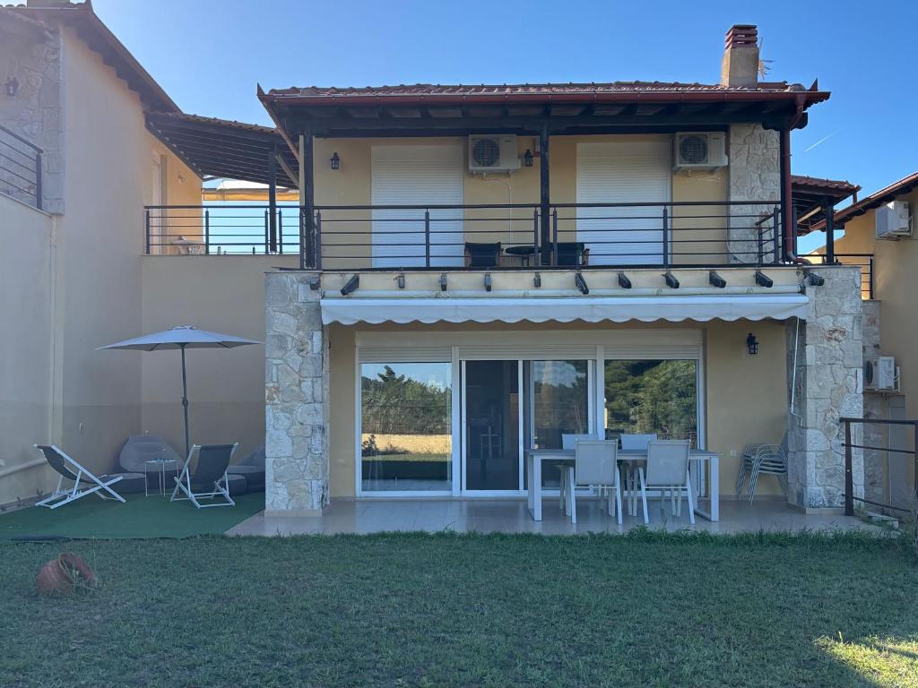a house with a balcony and a table and chairs at Villa Beauty in Paliouri
