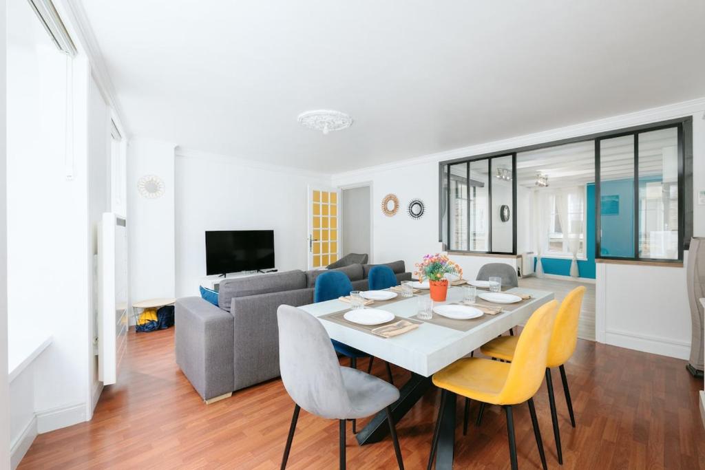a dining room and living room with a table and chairs at Le Triplex du Vœu Spacious Apartment in Cherbourg en Cotentin