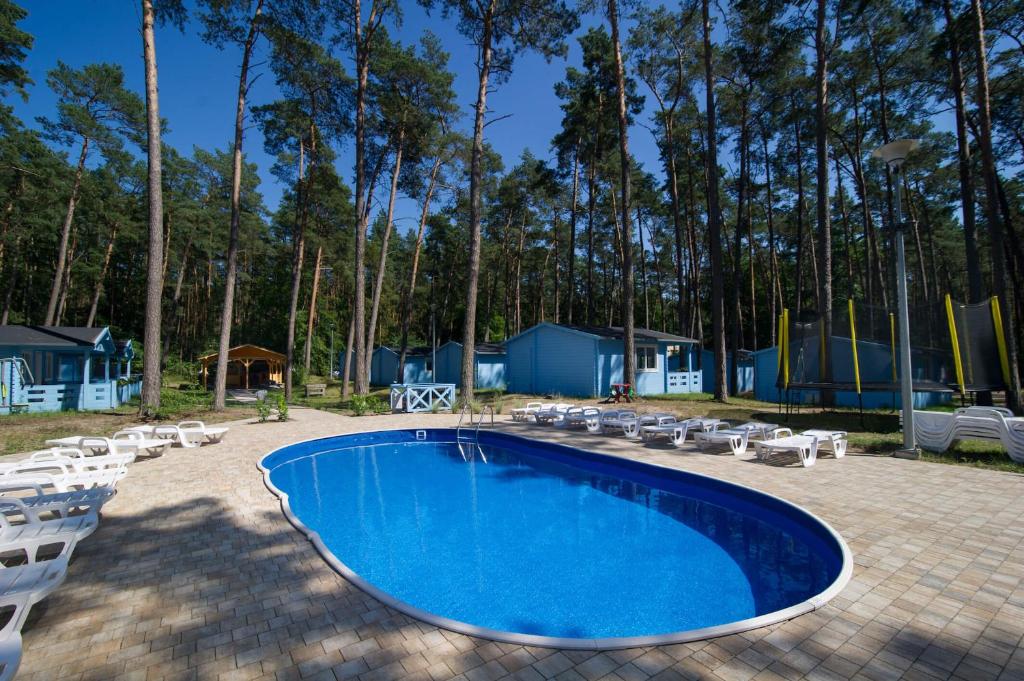 a swimming pool with chairs and a playground at Greckie Domki ZEUS in Stegna