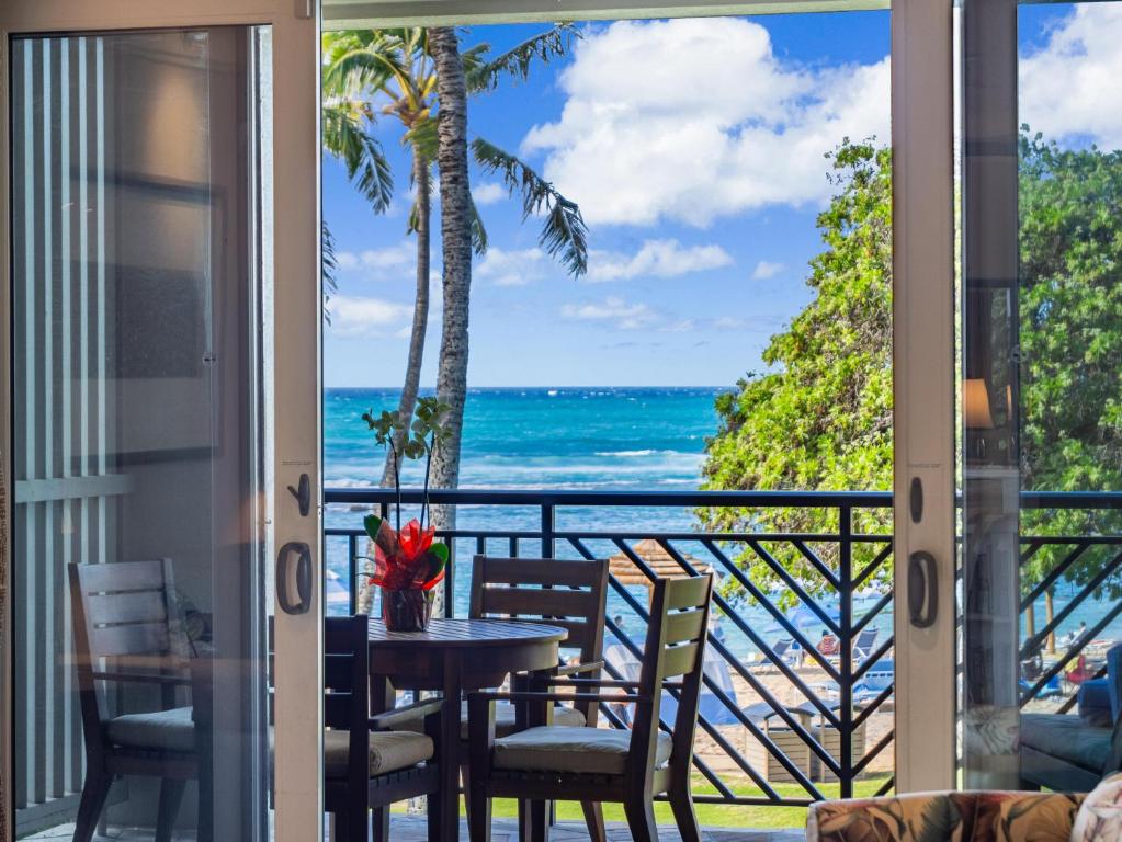 a balcony with a table and chairs and a view of the ocean at Villa 202 at Turtle Bay in Kahuku