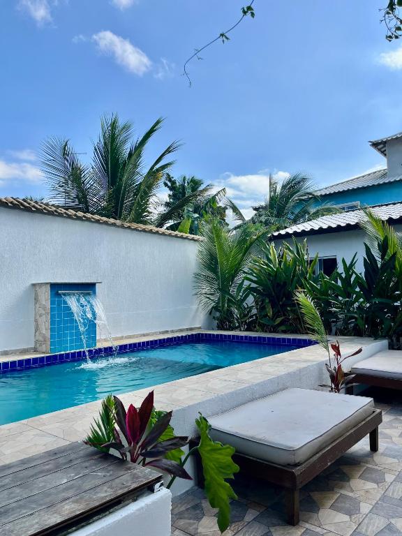 a swimming pool with a bench next to a house at Renascer Suites in Búzios