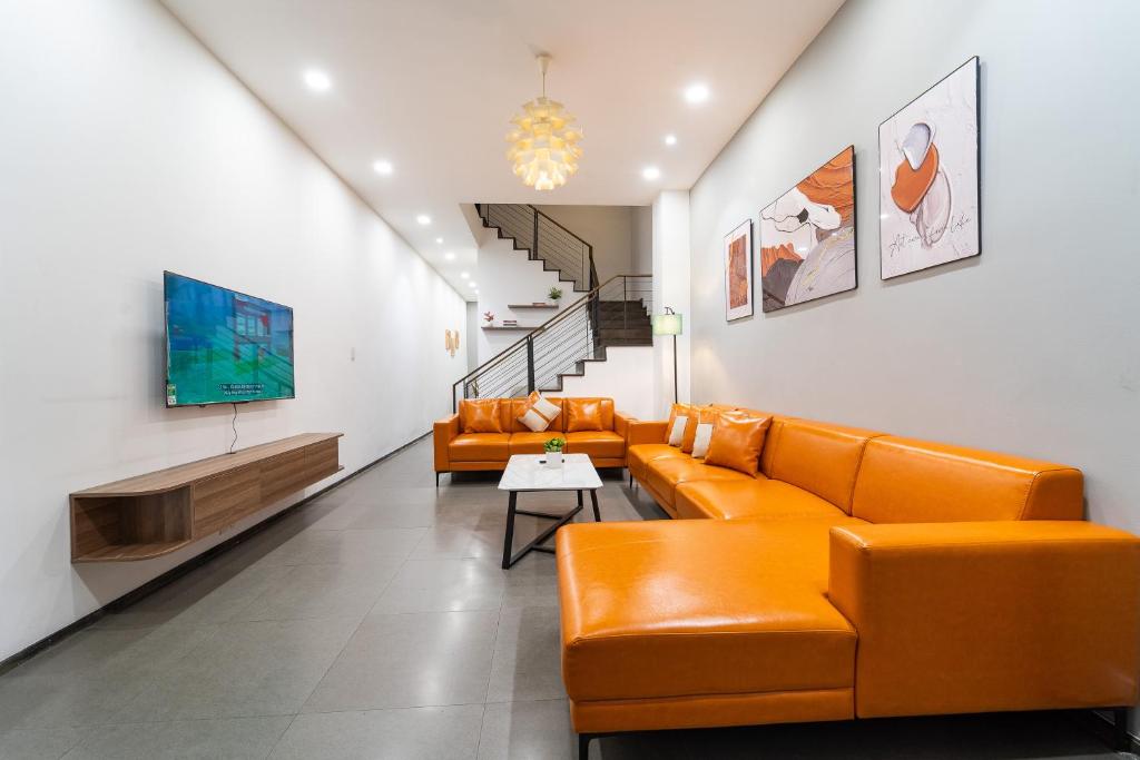 a living room with orange leather couches and a tv at 5BR Home - BBQ - City Centre - Free Pick Up for 3 nights in Ho Chi Minh City