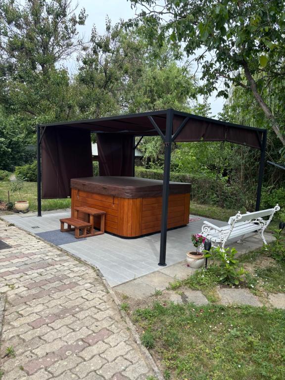 a gazebo with a bench and a table at Vidéki Vendégház in Doboz