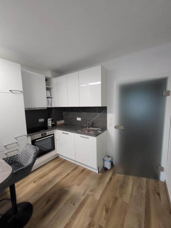 a small kitchen with white cabinets and a wooden floor at Apartment Karin in Langenwang