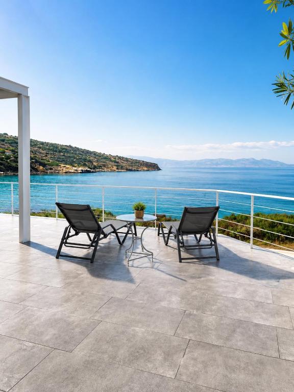 a patio with two chairs and a table and the ocean at Thalasson Beach House in Koroni