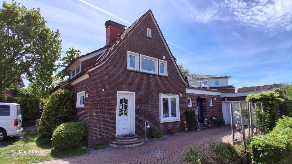 a red brick house with a white door at Haus Küstenglück in Neuharlingersiel
