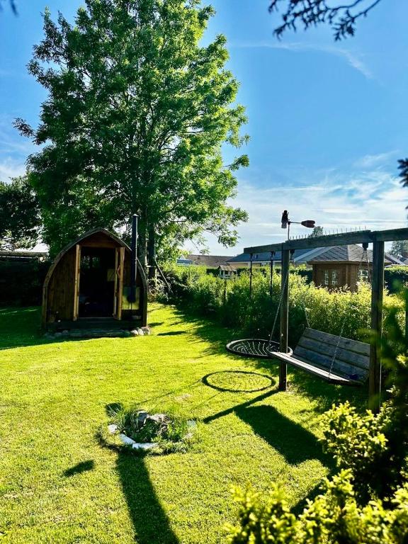 a garden with a bench and a tree and a tent at Chatka in Tappernøje