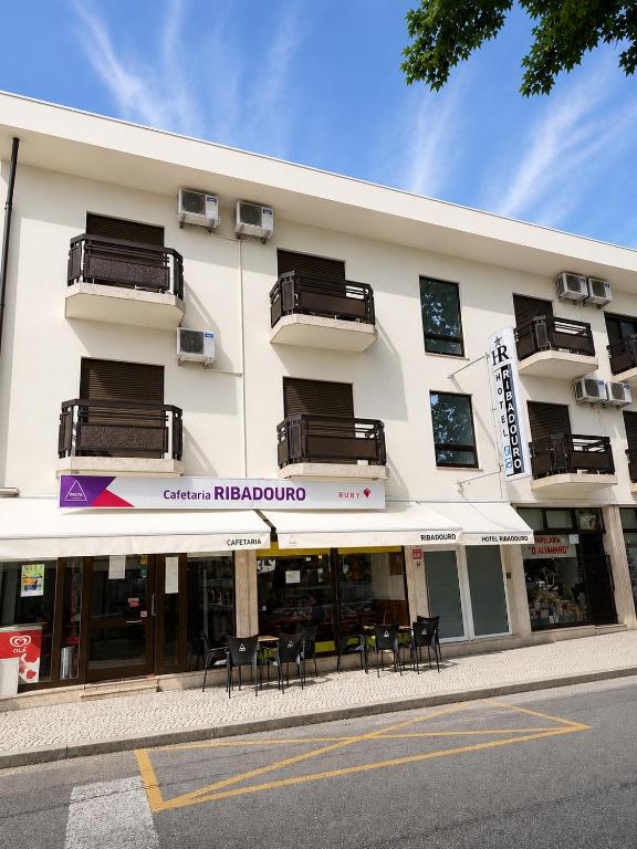 ein Gebäude mit Tischen und Stühlen davor in der Unterkunft Hotel Ribadouro in Alijó