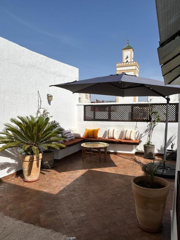 a patio with an umbrella and some plants and a table at Riad Dar Lina Logement entier in Rabat