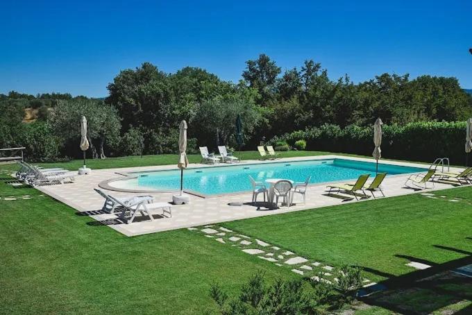 a swimming pool with chairs and a table in a yard at B&B La Camilla in Sipicciano