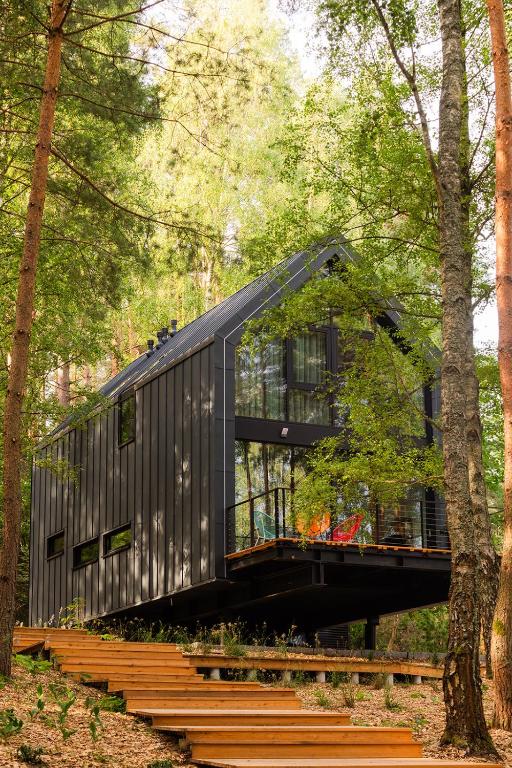 a black house in the middle of a forest at Między Drzewami - domy nad jeziorem Ukiel in Olsztyn